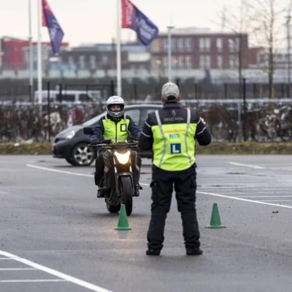 Instructeur van Motorrijschool Betti begeleidt een student tussen de pylonen